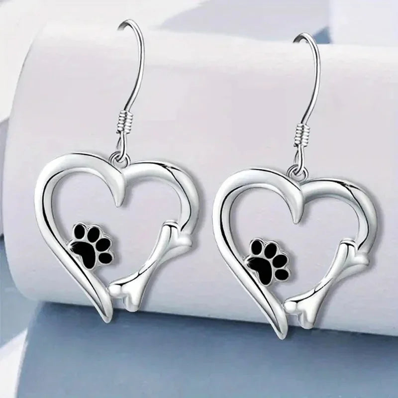 Silver dangling earrings with a heart and paw print design
