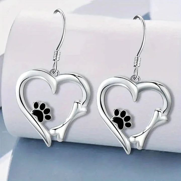 Silver dangling earrings with a heart and paw print design
