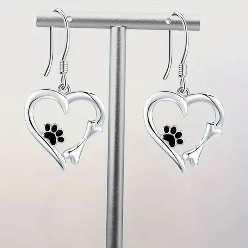Silver dangling earrings with a heart and paw print design