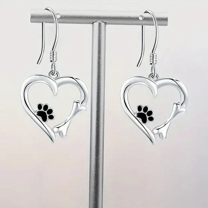 Silver dangling earrings with a heart and paw print design